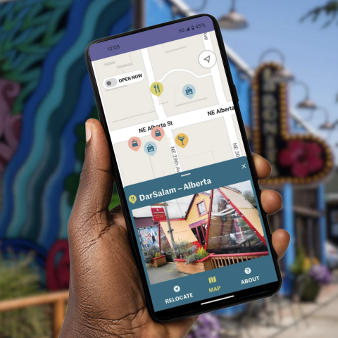 hand holding phone on a city street with Near Me Now app opened